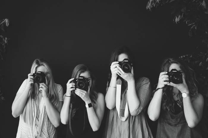 A black and white photo of four beginners photographers holding DSLR cameras