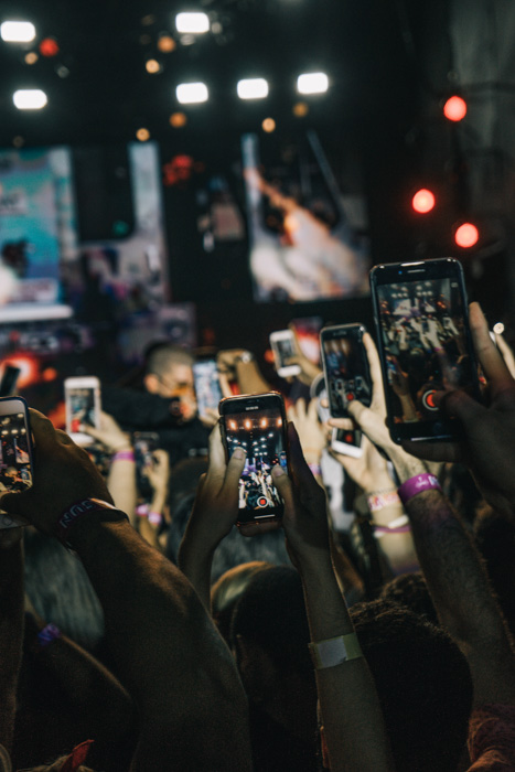 A concert photography shot of the audience all taking photos on their smartphone for Instagram profile pictures
