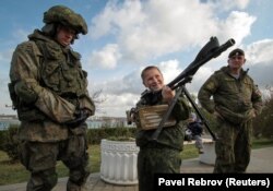 UKRAINE -- A boy holds a machine gun at a military hardware exhibition during a swear-in ceremony for new recruits of the Russian military-patriotic club "Yunarmia" (Young army) in the Black Sea port of Sevastopol, Crimea, October 27, 2018.