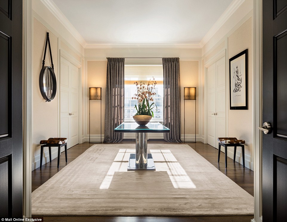 The doors to the suite open to reveal a smart entrance hall with light and airy furnishings. A pot of fresh orchids sits on a mirrored table, with the purple-hued flowers adding a splash of colour to the cavernous space