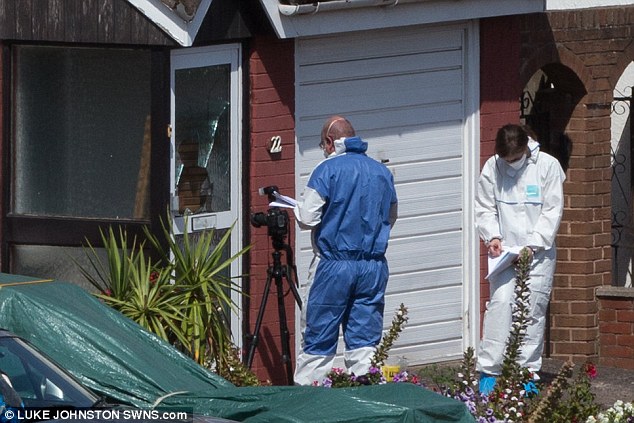 Forensic teams are pictured inspecting a broken glass door at the scene of the tragedy