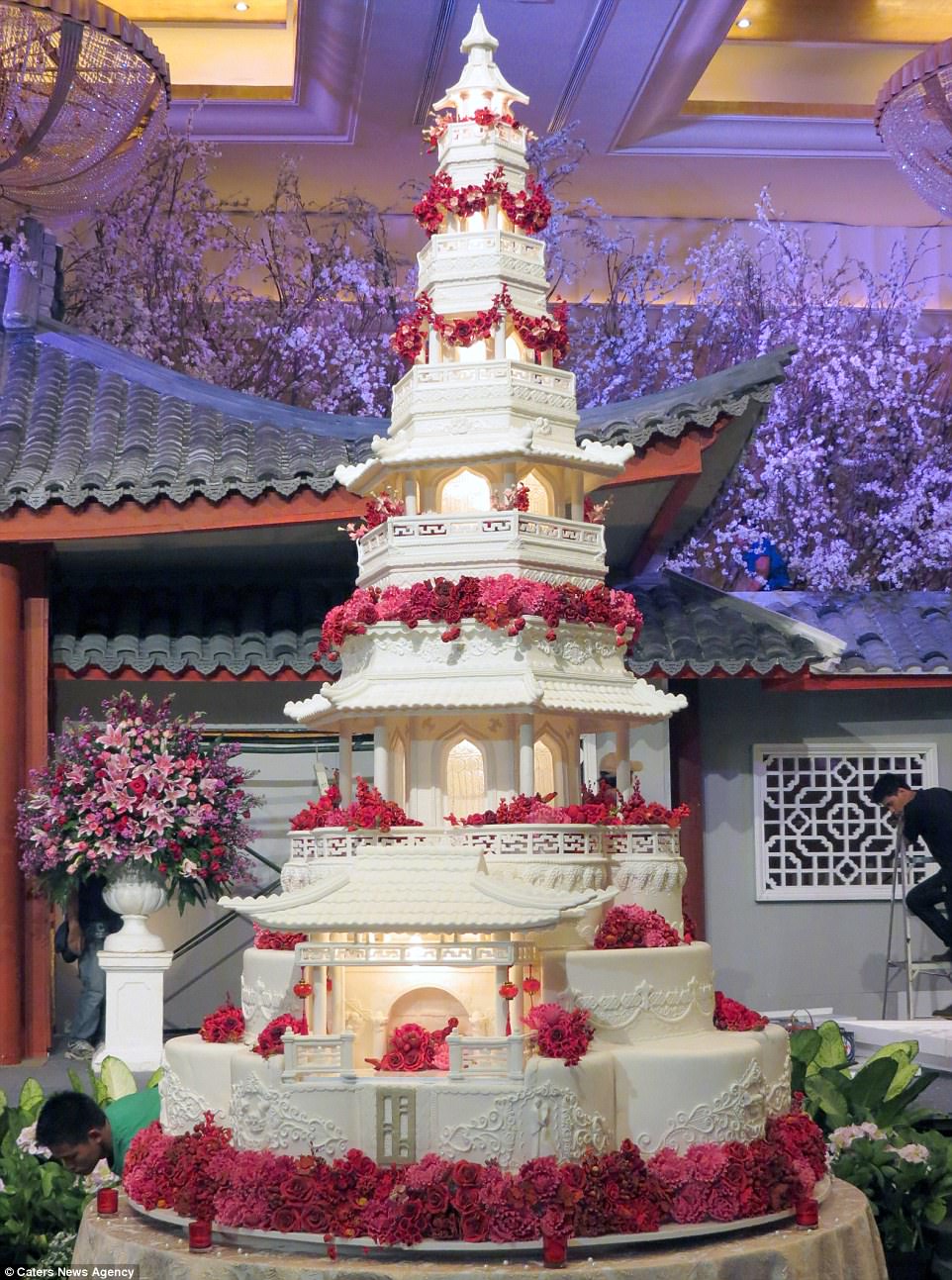This breathtaking Japanese pagoda cake has an astonishing nine tiers. It features intricate icing detail, including a loved up couple on the bottom tier, as well as Japanese inspired symbols. Red flowers contrast against the white of the cake