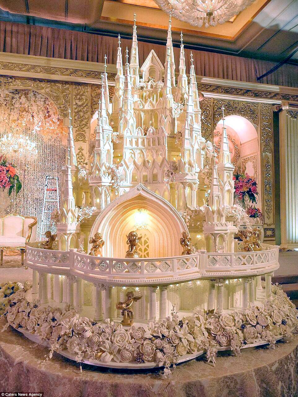 This cathedral wedding cake has been decorated with hundreds of delicate sugar flowers, some of which have been brushed with silver and gold. Adorning the outside are golden cherubs. One of these cakes takes about a month to make