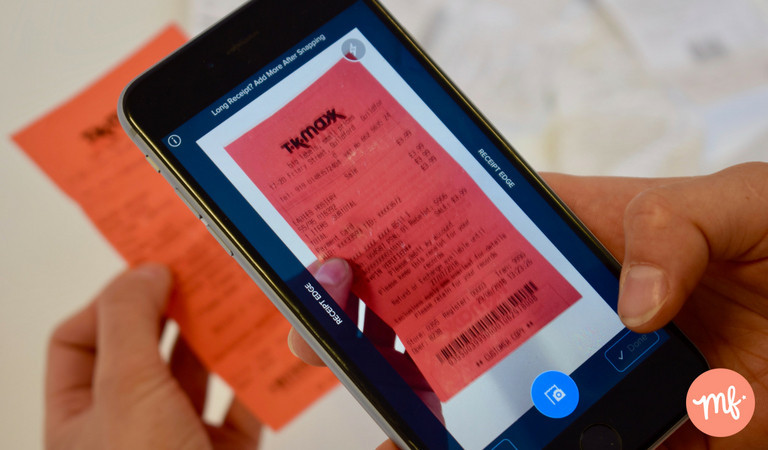 Hand holding black iPhone scanning a red TK Maxx receipt