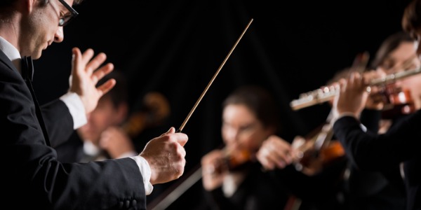 A conductor during a performance at a concert hall conducting the orchestra.