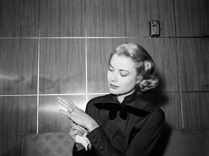 Grace Kelly showing the ruby and diamond eternity band Prince Rainier proposed with to photographers at her parents home in Philadelphia. Photo Getty