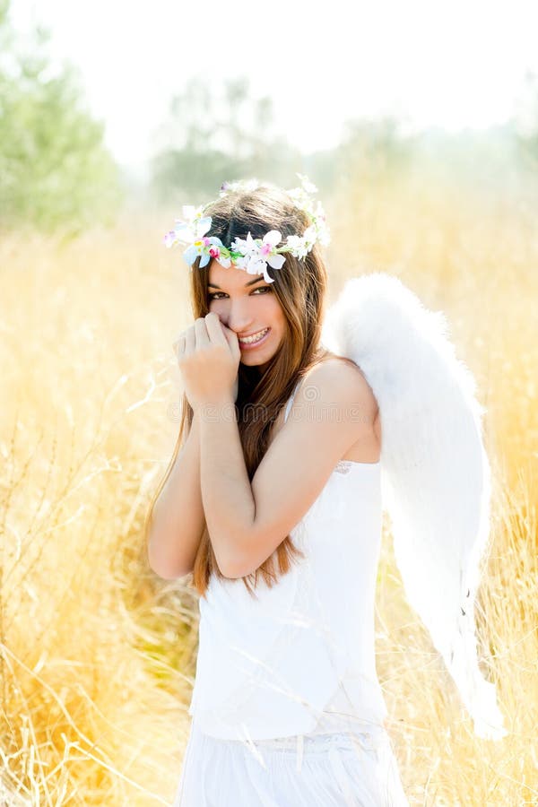 Angel girl in golden field with white wings. Angel etchnic woman in golden field with feather white wings and flowers crown stock photography