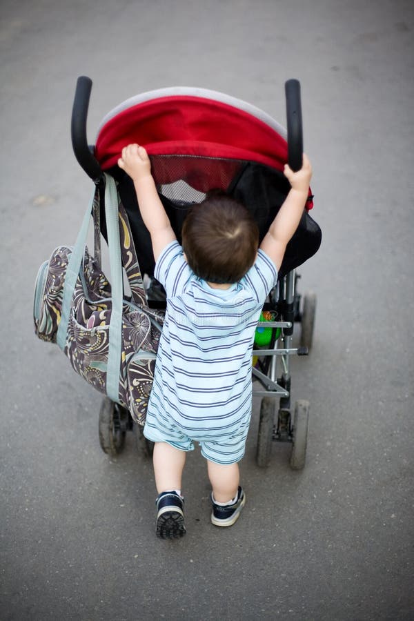 Baby pushing stroller. Funny baby pushing stroller on alley stock images