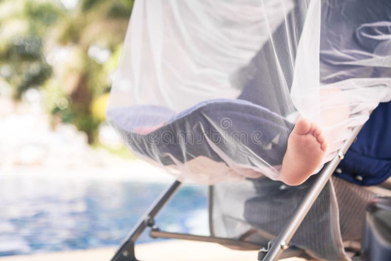 Baby sleeping in baby stroller during summer holidays in warm country during hot day while travelling. Baby sleeping in baby stroller covered with mosquito net royalty free stock photo