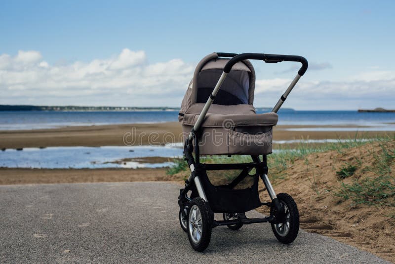 Baby stroller on beach. Baby stroller in park at sunny day stock photo