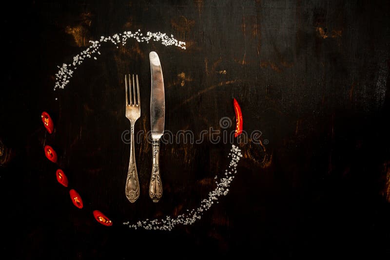 Circle frame composition Chilli peppers and spices with fork and knife on the black background. Frame of Indian spices and herbs. royalty free stock images