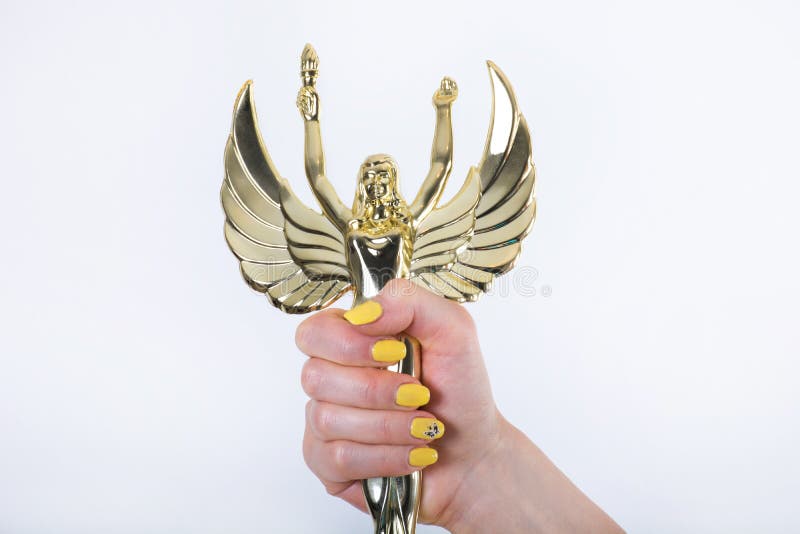 Golden Angel statue with torch and opened wings in female hand. Beautiful golden female angel statue with torch and opened wings in woman hand with yellow stock photo