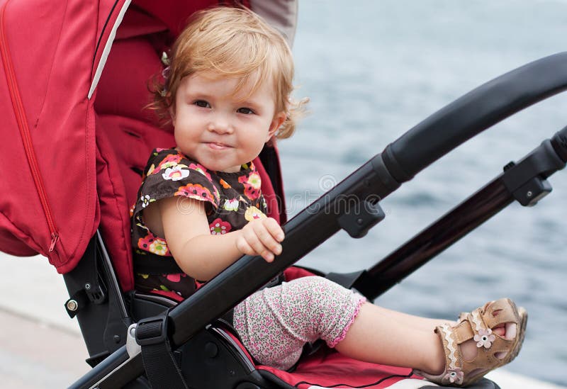 Happy baby in a stroller. Smiling baby in a stroller in the background of the sea stock images