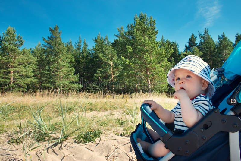 Little baby boy sitting in the stroller on summer day. Nine month old baby boy sitting in the stroller on beautiful summer day royalty free stock image