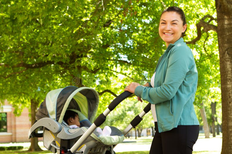 Mom pushing her baby in a stroller. Hispanic mom pushing her baby in a stroller royalty free stock photo