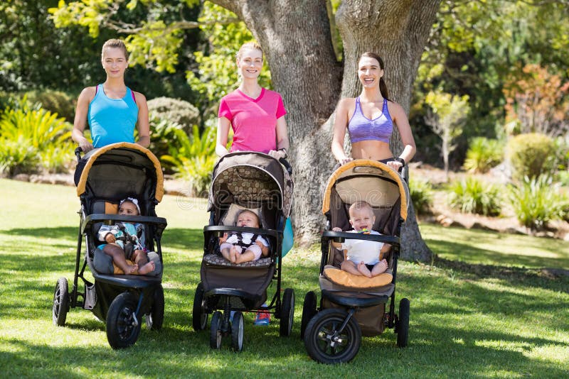 Women standing with the baby stroller. In park stock images