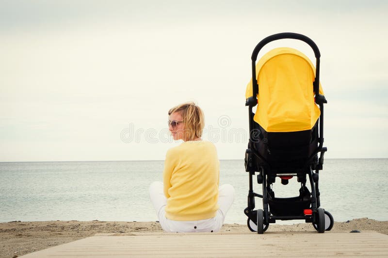 Young mother relaxing on beach with baby stroller royalty free stock photos